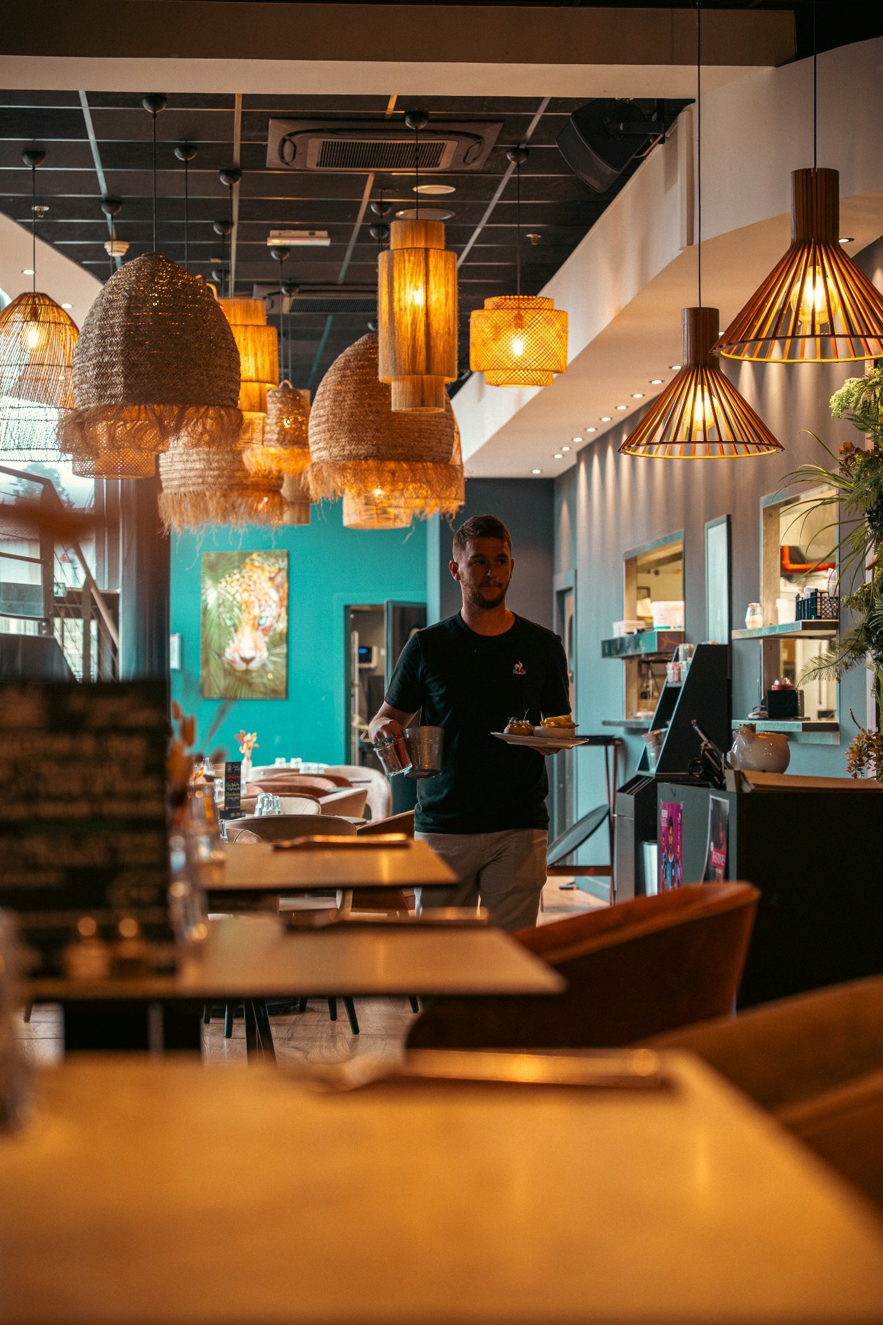 Salle du restaurant WOODS à Bourgoin-Jallieu avec décoration végétale, murs verts et lumières tamisées ambiance chic.