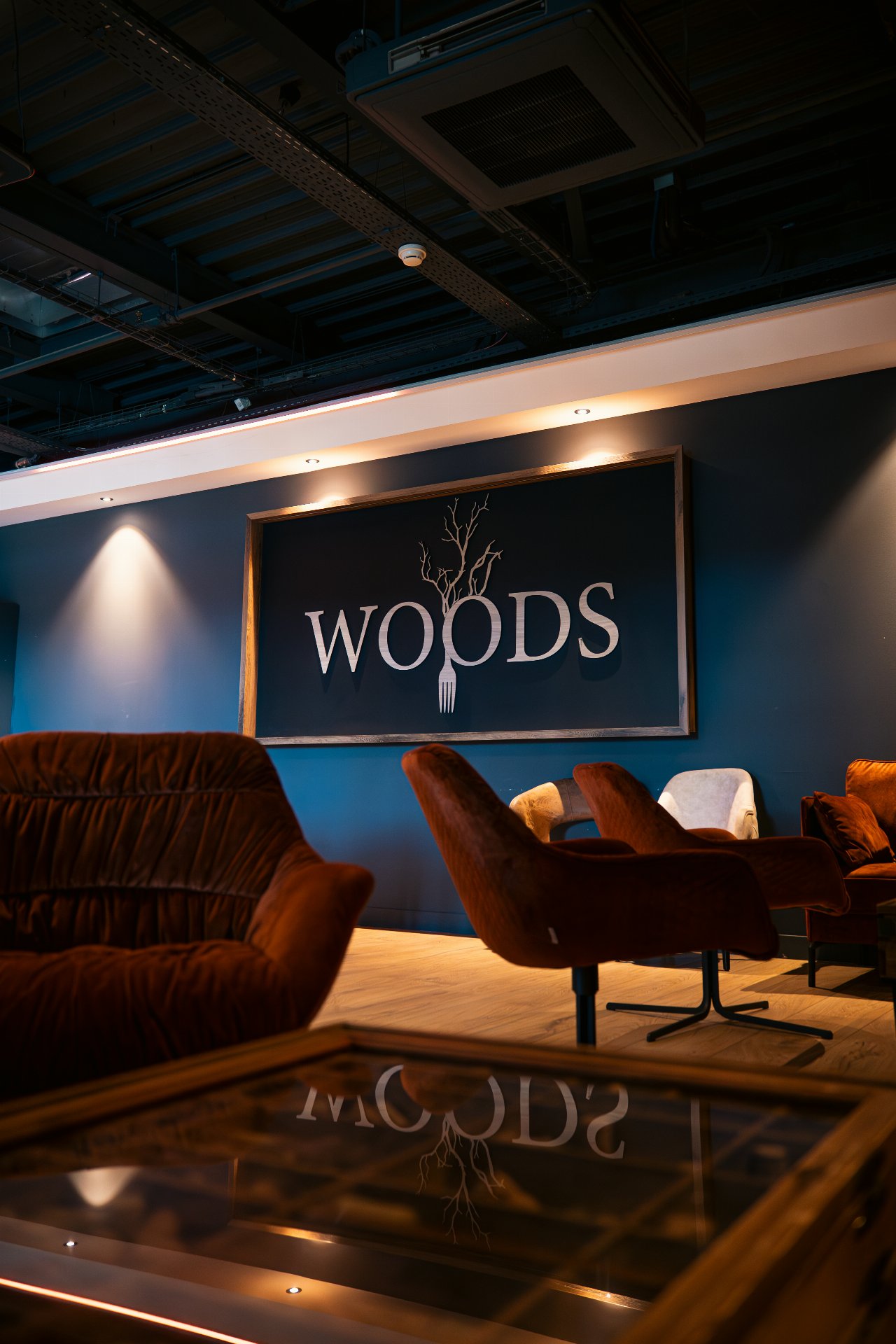 Salle privative du Woods, fauteuil confortable et table basse, déco au mur